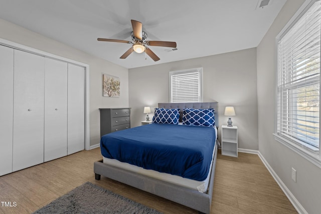 bedroom with light wood-type flooring, a closet, multiple windows, and ceiling fan