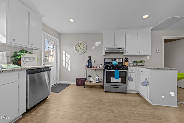 kitchen with light stone countertops, white cabinets, stainless steel appliances, and light wood-type flooring