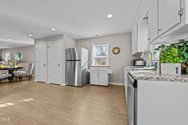 kitchen with light hardwood / wood-style flooring, sink, white cabinetry, light stone counters, and stainless steel appliances