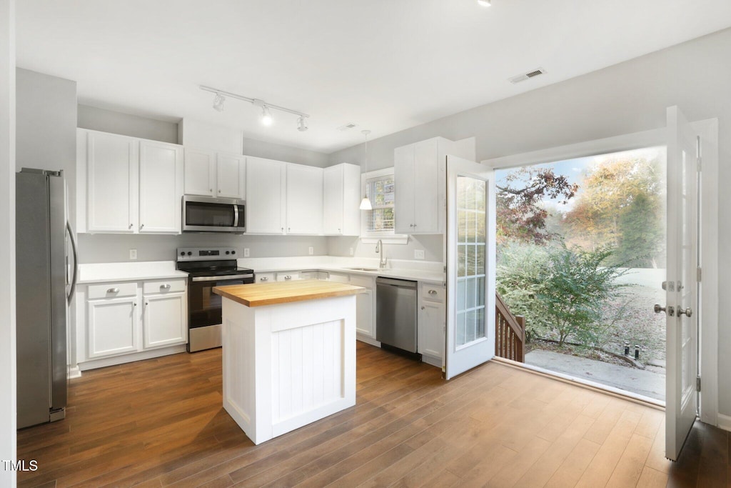 kitchen with white cabinetry, sink, stainless steel appliances, wood counters, and a kitchen island