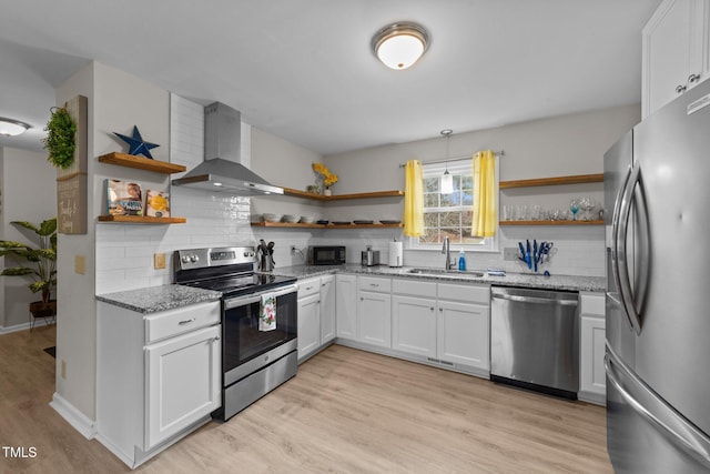 kitchen featuring appliances with stainless steel finishes, decorative backsplash, white cabinets, sink, and wall chimney exhaust hood