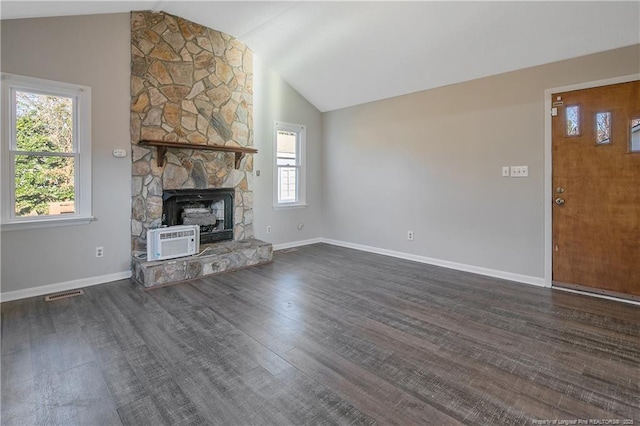 unfurnished living room with dark hardwood / wood-style flooring, a stone fireplace, lofted ceiling, and a wealth of natural light