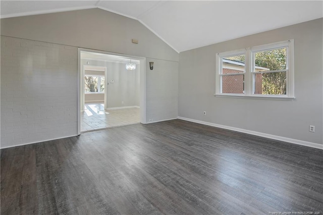 empty room featuring a chandelier, dark hardwood / wood-style flooring, a healthy amount of sunlight, and lofted ceiling