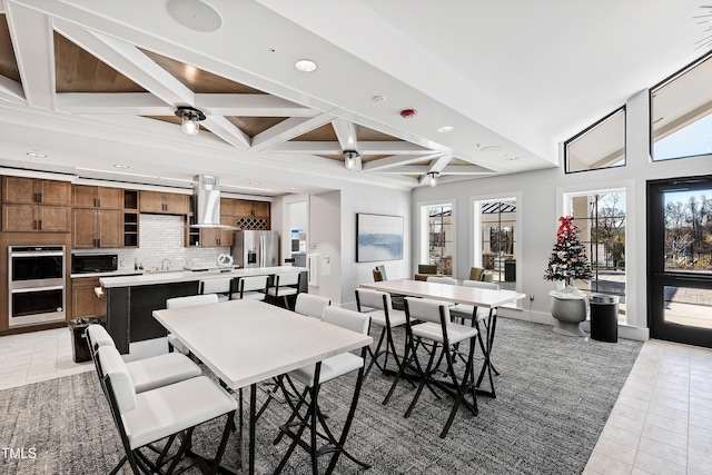 dining area with beam ceiling, coffered ceiling, light tile patterned floors, and ceiling fan