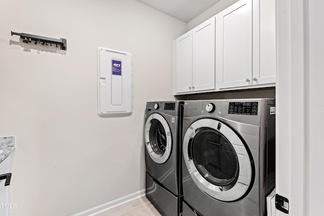 clothes washing area with washer and dryer and cabinets