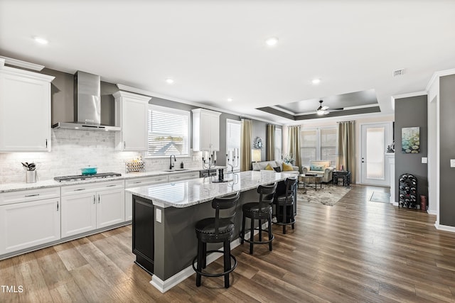 kitchen featuring white cabinetry, wall chimney range hood, and a kitchen island