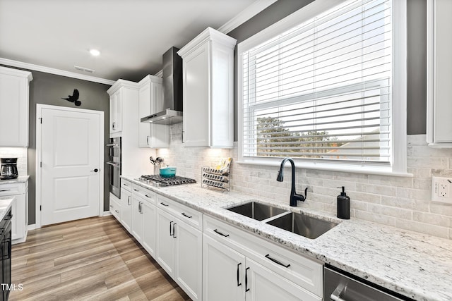 kitchen with white cabinetry, sink, light stone counters, and wall chimney exhaust hood