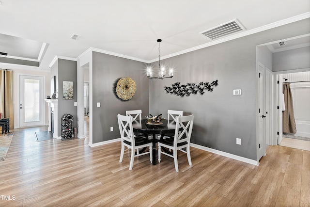 dining area featuring ornamental molding, light hardwood / wood-style floors, and a chandelier