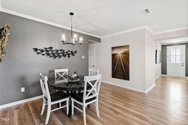 dining space featuring hardwood / wood-style flooring, crown molding, and a notable chandelier