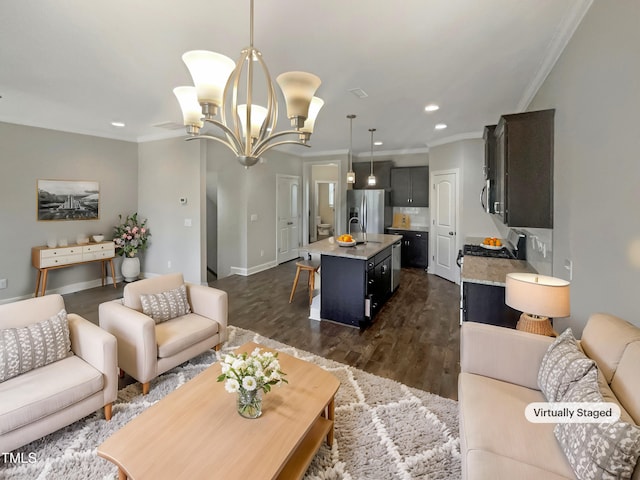 living room with a notable chandelier, sink, ornamental molding, and dark wood-type flooring