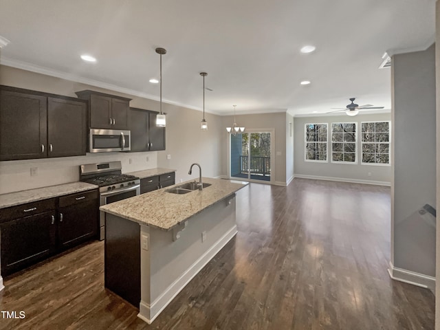 kitchen with sink, stainless steel appliances, an island with sink, decorative light fixtures, and ceiling fan with notable chandelier