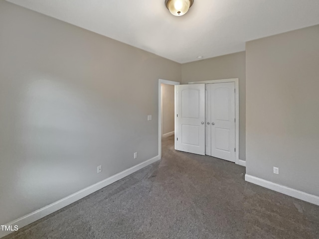 unfurnished bedroom featuring a closet and dark carpet