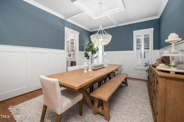 dining space featuring beamed ceiling, coffered ceiling, a notable chandelier, crown molding, and light hardwood / wood-style flooring