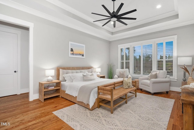 bedroom with crown molding, ceiling fan, a raised ceiling, and light hardwood / wood-style floors