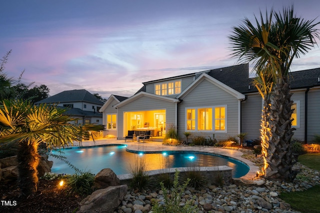 back house at dusk with a patio and pool water feature