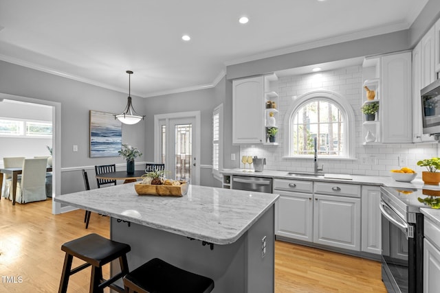 kitchen with appliances with stainless steel finishes, a center island, white cabinetry, and open shelves