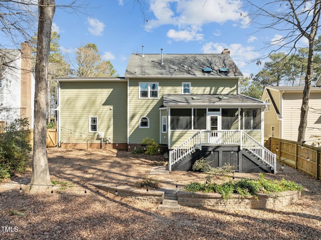 rear view of property featuring a sunroom, fence, and stairway