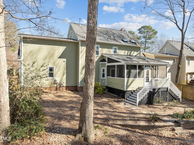 back of property with a sunroom, stairs, and a chimney