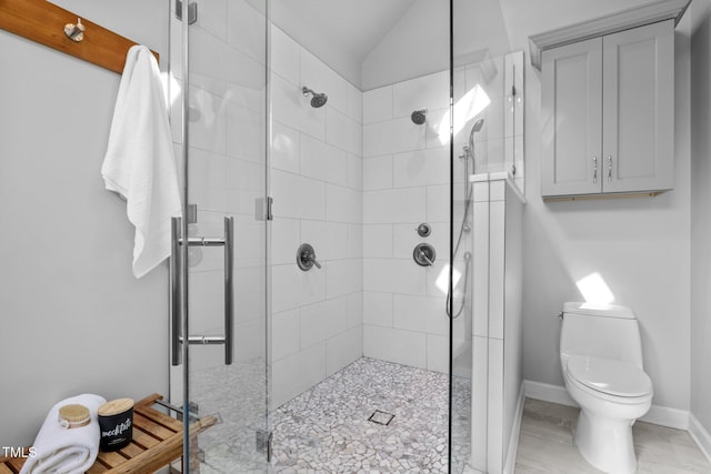 full bathroom featuring a stall shower, baseboards, vaulted ceiling, and toilet