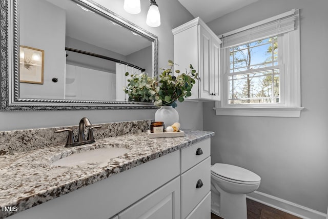 bathroom with toilet, a shower with curtain, vanity, and baseboards