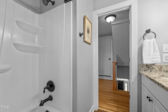 bathroom featuring wood finished floors, vanity, and bathing tub / shower combination