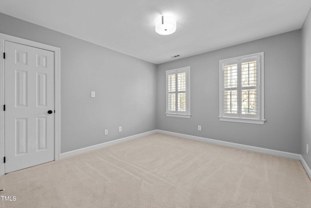 spare room featuring light carpet, visible vents, and baseboards