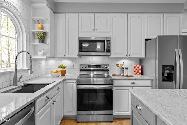 kitchen featuring stainless steel appliances, open shelves, white cabinetry, and light stone countertops