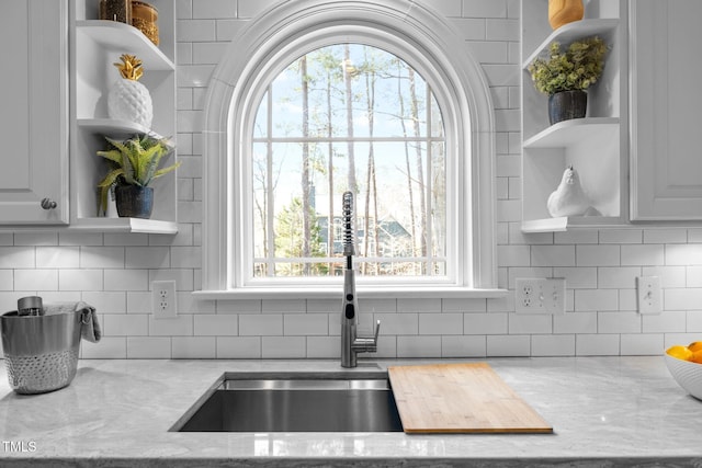 kitchen featuring white cabinets, light stone countertops, open shelves, and backsplash