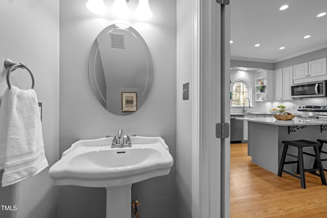 bathroom with a sink, tasteful backsplash, wood finished floors, and recessed lighting