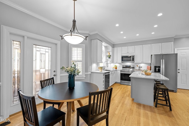 kitchen featuring appliances with stainless steel finishes, a center island, hanging light fixtures, white cabinetry, and a sink