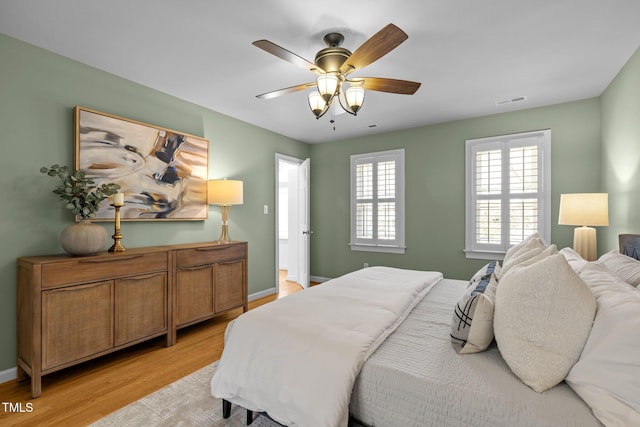 bedroom featuring light wood-type flooring, visible vents, ceiling fan, and baseboards