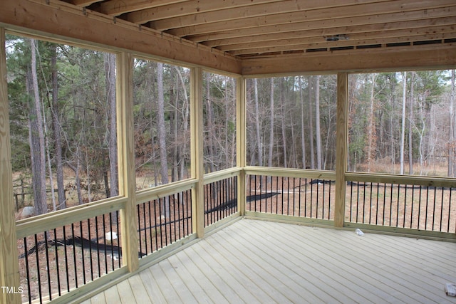 unfurnished sunroom with a wooded view and a healthy amount of sunlight