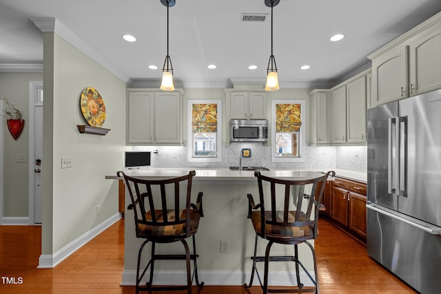 kitchen with decorative light fixtures, backsplash, crown molding, appliances with stainless steel finishes, and a kitchen breakfast bar