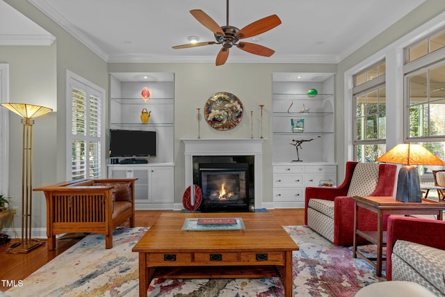 living room with crown molding, built in shelves, and wood-type flooring