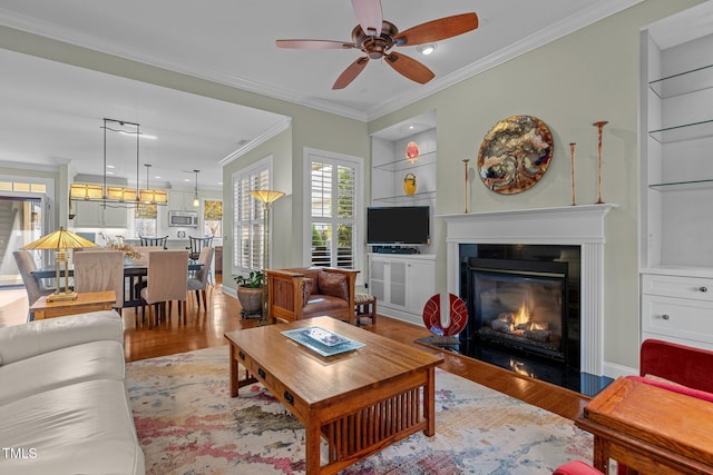 living room with ceiling fan, light hardwood / wood-style flooring, ornamental molding, and built in features