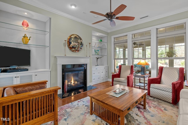 living room with light hardwood / wood-style floors, ceiling fan, built in shelves, and ornamental molding