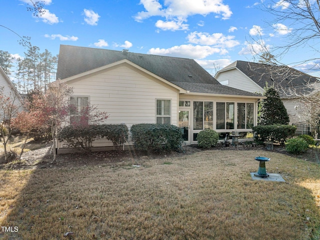 back of house featuring a lawn and a sunroom