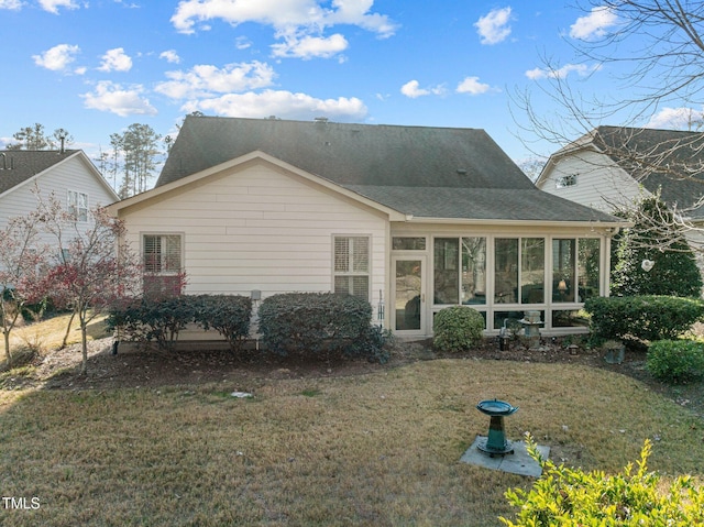 rear view of house featuring a lawn and a sunroom