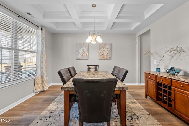 dining space featuring wood-type flooring, beamed ceiling, an inviting chandelier, crown molding, and coffered ceiling