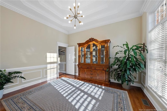 living area with a raised ceiling, dark hardwood / wood-style flooring, ornamental molding, and a chandelier