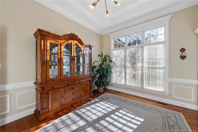 interior space with a chandelier, dark hardwood / wood-style flooring, a raised ceiling, and crown molding