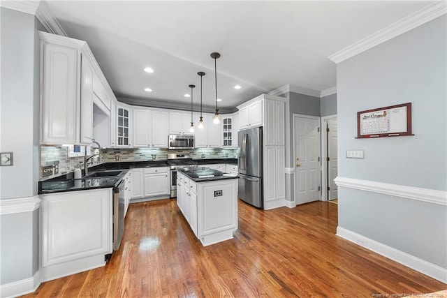 kitchen featuring sink, a kitchen island, decorative light fixtures, white cabinets, and appliances with stainless steel finishes