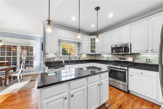 kitchen featuring appliances with stainless steel finishes, a kitchen island, sink, decorative light fixtures, and white cabinetry