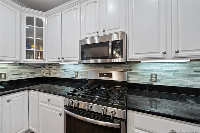 kitchen featuring decorative backsplash, appliances with stainless steel finishes, white cabinetry, and dark stone counters