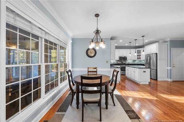 dining space featuring ornamental molding, light hardwood / wood-style flooring, and an inviting chandelier