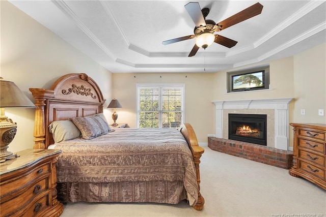 carpeted bedroom with a brick fireplace, a raised ceiling, ceiling fan, and crown molding