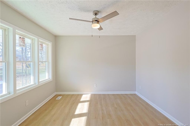 unfurnished room with ceiling fan, a textured ceiling, and light wood-type flooring