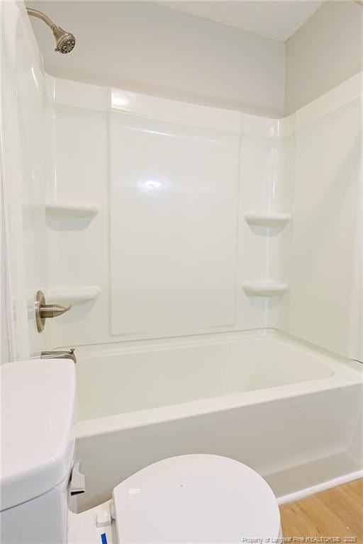 bathroom with hardwood / wood-style floors, toilet, and shower / bathing tub combination