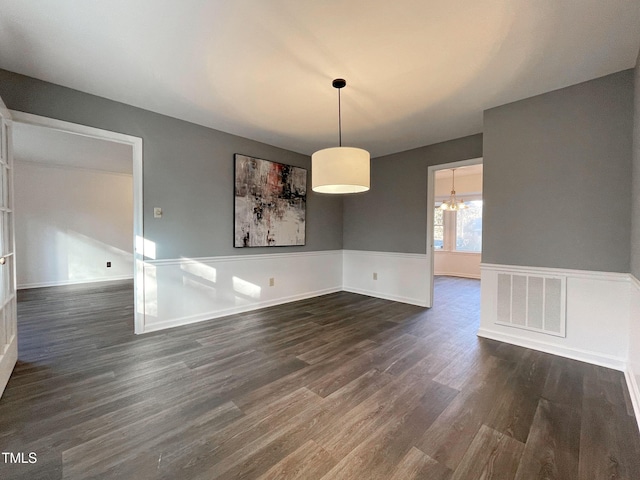 unfurnished dining area featuring dark wood-type flooring and a chandelier