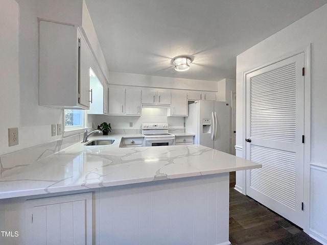 kitchen with sink, white cabinetry, kitchen peninsula, white appliances, and light stone countertops